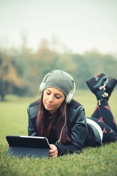 Jong meisje in park luisteren muziek — Stockfoto