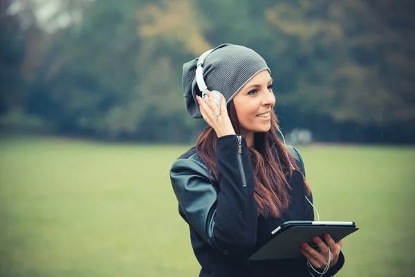 Chica joven en el parque escuchando música — Foto de Stock