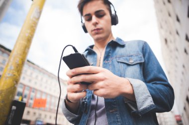 Kulaklıklı genç adam müzik dinliyor.