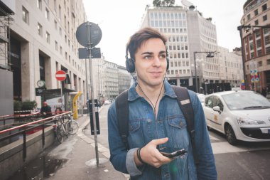 Kulaklıklı genç adam müzik dinliyor.