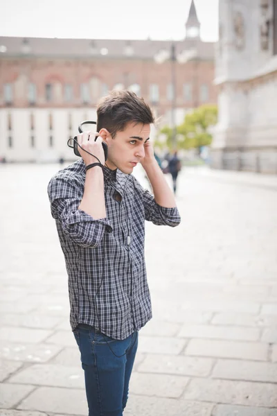 Young handsome alternative dark model man in town listening to m — Stock Photo, Image