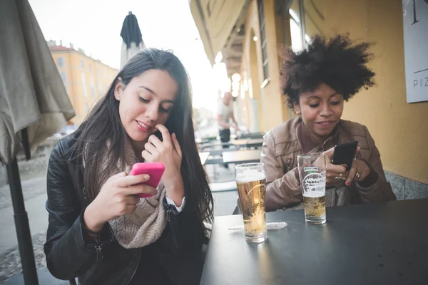 Two multiethnic beautiful young woman black and caucasian using — Stock Photo, Image