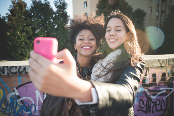 Two multiethnic girls taking selfie
