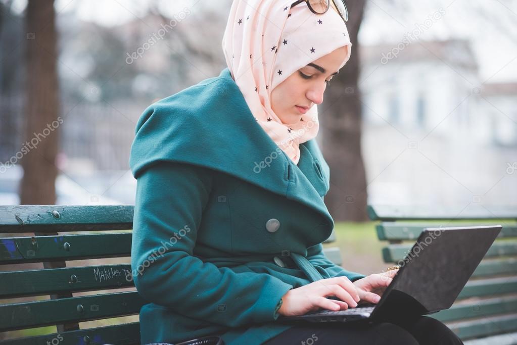 muslim woman at  park with laptop