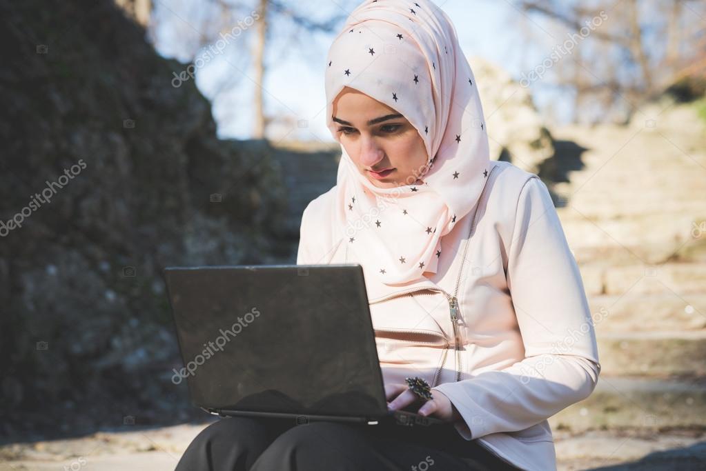 muslim woman at  park with laptop