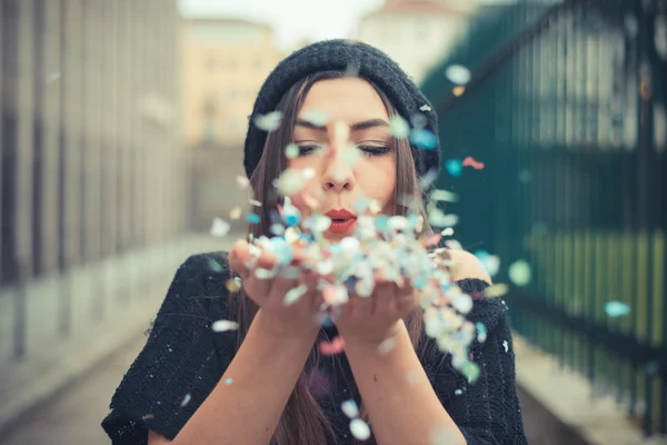 Mooie jonge vrouw blazen confetti — Stockfoto