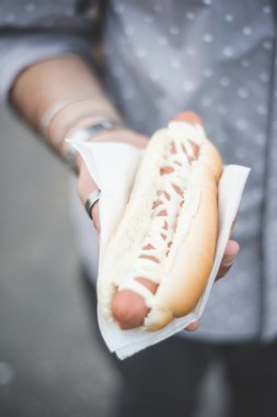 Sosisli sandviç tutan genç adam el