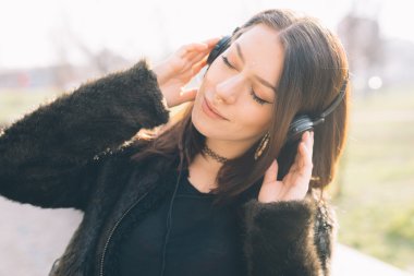 Genç ve güzel bir kadın kulaklıkla müzik dinliyor.