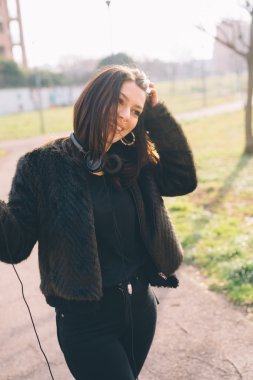 Genç ve güzel bir kadın kulaklıkla müzik dinliyor.