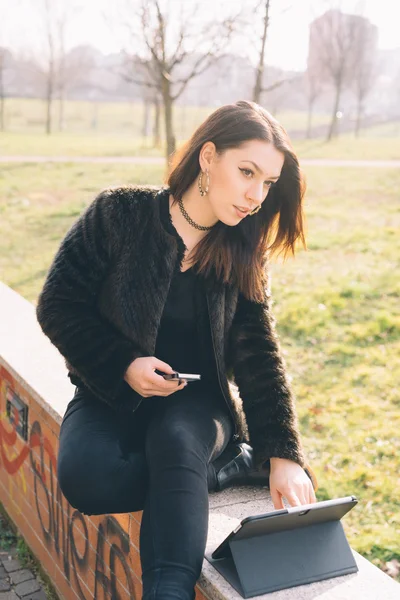 Молодая красивая женщина с помощью планшета и смартфона — стоковое фото