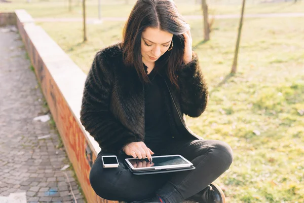 Tablet ve akıllı telefon kullanan genç güzel kadın — Stok fotoğraf