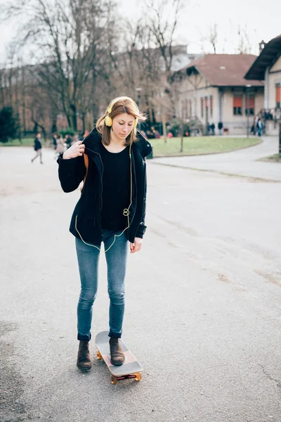 Hipster meisje met skate en hoofdtelefoon — Stockfoto