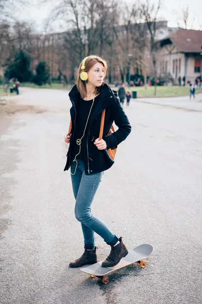 Hipster menina com skate e fones de ouvido — Fotografia de Stock