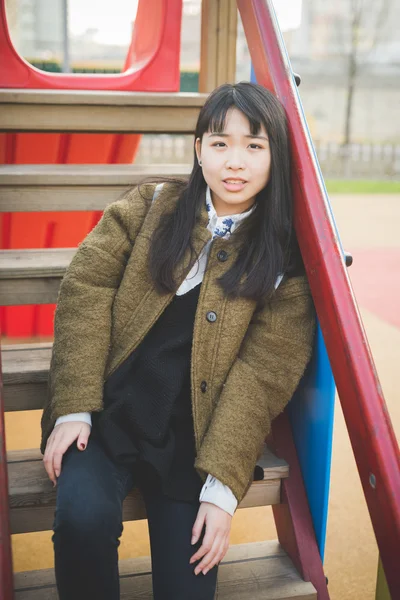 Asian woman in playground in city — Stock Photo, Image