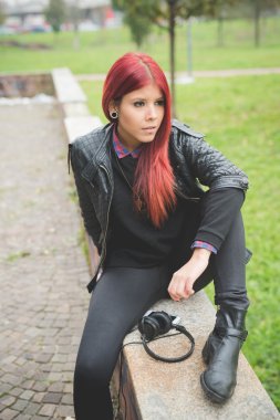 Young woman sitting in park with headphones