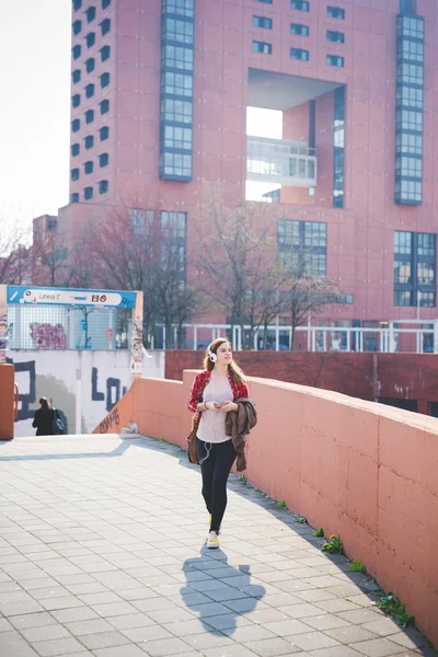 Hipster woman walking in city and listening music — Stockfoto