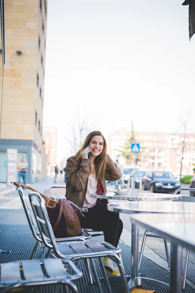 Женщина сидит в кафе и разговаривает по телефону — стоковое фото