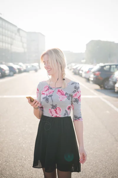 Blonde vrouw buiten luisteren muziek — Stockfoto