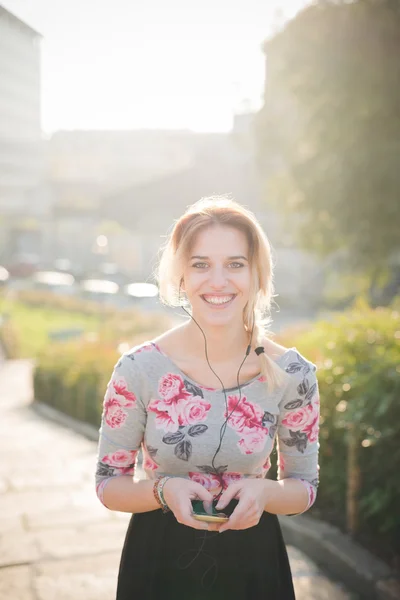 Blonde vrouw buiten luisteren muziek — Stockfoto