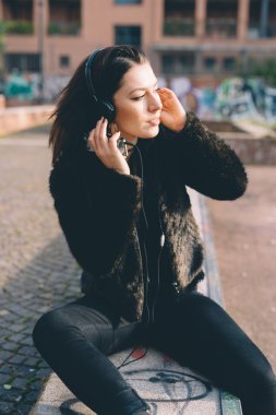 Genç ve güzel bir kadın kulaklıkla müzik dinliyor.