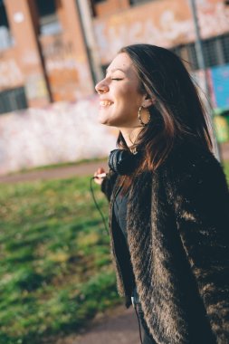 Genç ve güzel bir kadın kulaklıkla müzik dinliyor.