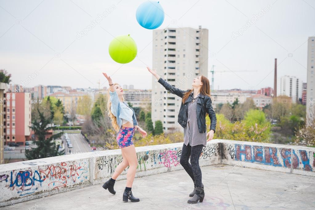 Two beautiful girls playing with balloons