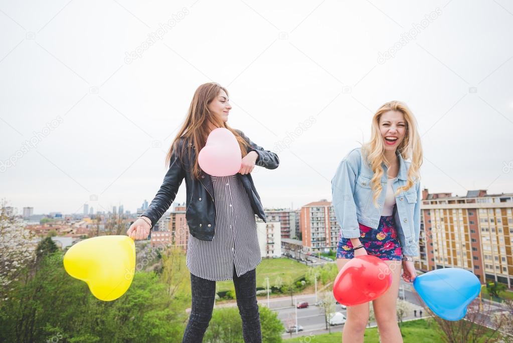 Two beautiful girls playing with balloons