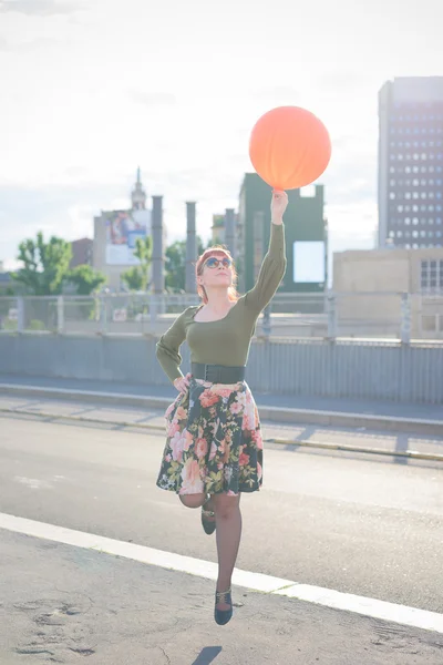 Молодая красивая рыжая женщина играет с воздушным шаром — стоковое фото