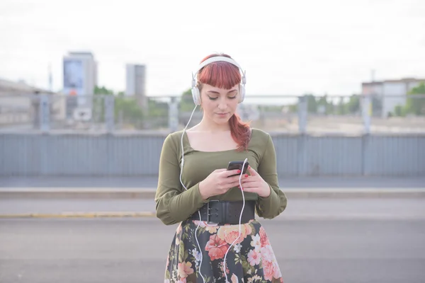 Junge hübsche rothaarige Frau hört Musik — Stockfoto