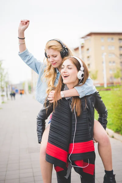 Dos hermosas amigas chica escuchando música sonriendo —  Fotos de Stock