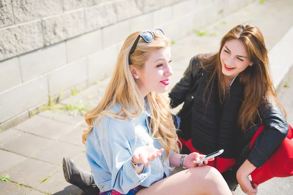 Two young women friends using smartphone smiling — Stock Photo, Image