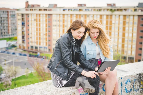 Två unga kvinnor vänner använder tablet — Stockfoto