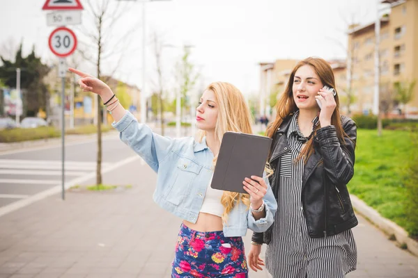 Dos amigas jóvenes usando dispositivos — Foto de Stock