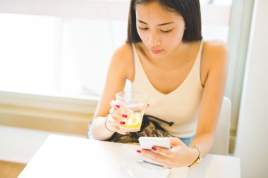Woman drinking a juice and using a smartphone