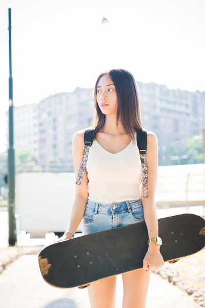 Asiatic woman holding a skateboard — Stok fotoğraf