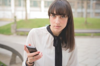 bir akıllı telefon kullanarak bir şehir parkında iş kadını