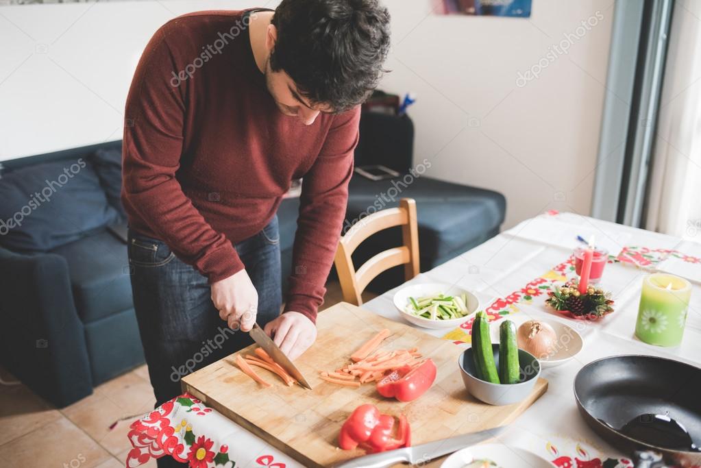 Young man cutting some carrots with knife