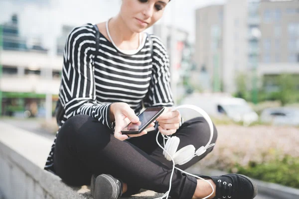 Mulher colocando fones de ouvido em seu smartphone — Fotografia de Stock