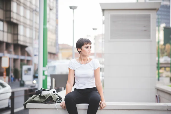 Woman sitting on a small wall in the city — Stockfoto