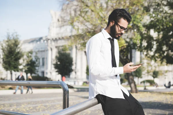 Geschäftsmann stützt sich mit Smartphone auf Stange — Stockfoto