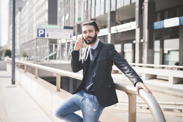 Smartphone kullanarak direğe yaslanmış işadamı 