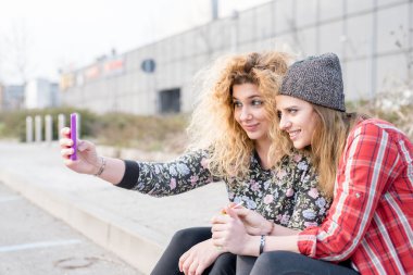 bir smartphone kullanarak kaldırım üzerinde oturan kadın