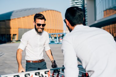 Masa futbolu oynayan Modern iş adamları