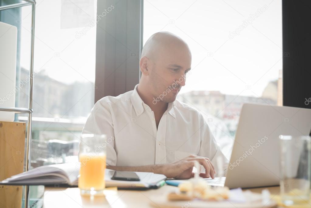 businessman sitting in a bar using a laptop 