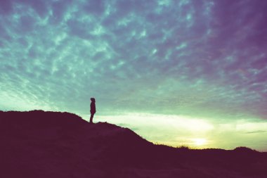 bir tepe üzerinde duran bir adam silüeti 
