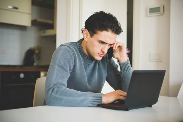 Az ember ül beszél a smartphone használ laptop — Stock Fotó