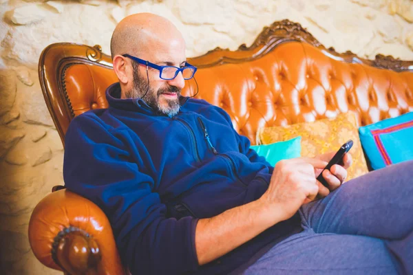 Man on vintage couch, holding smartphone — Stock Photo, Image