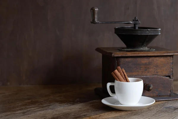 Molino para café con una taza blanca y canela . Imagen de archivo