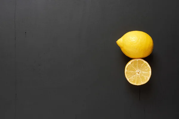 Limón y rodajas de limón. Liquidación fondo negro . Imágenes de stock libres de derechos