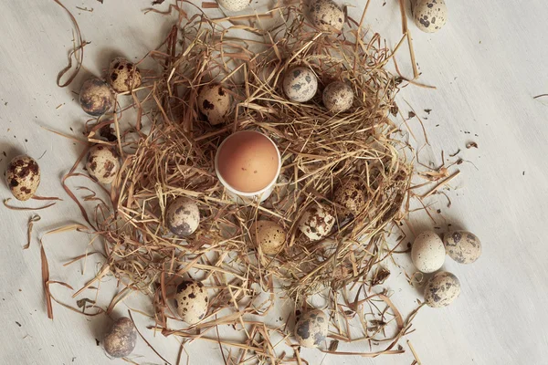 Ägg i hö häckar på gamla träbord bakgrund. — Stockfoto